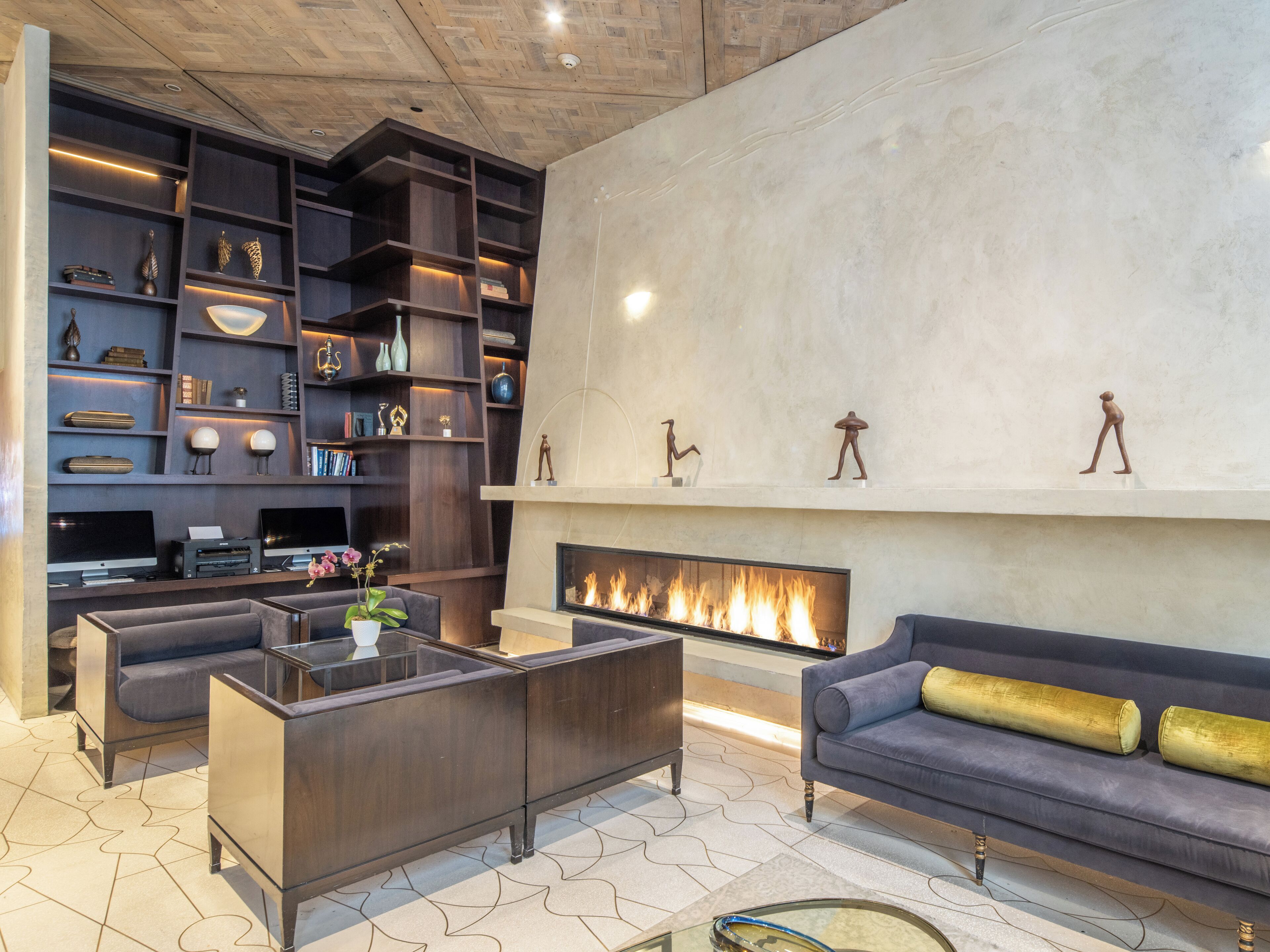 A modern living room with a fireplace, dark wood shelving, and comfortable seating.