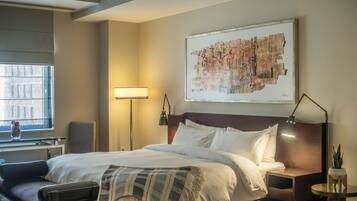 A hotel room with a large bed, bedside tables, a desk, a chair, a lamp, and a window.