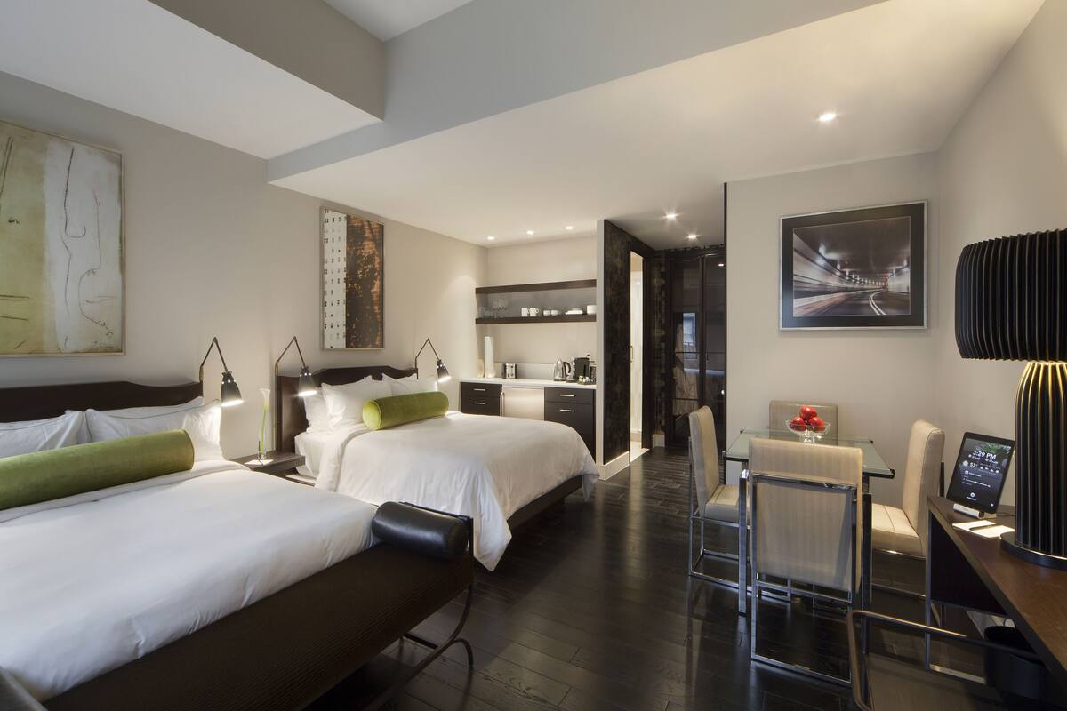 Una habitación de hotel moderna con dos camas, un comedor y una cocina.