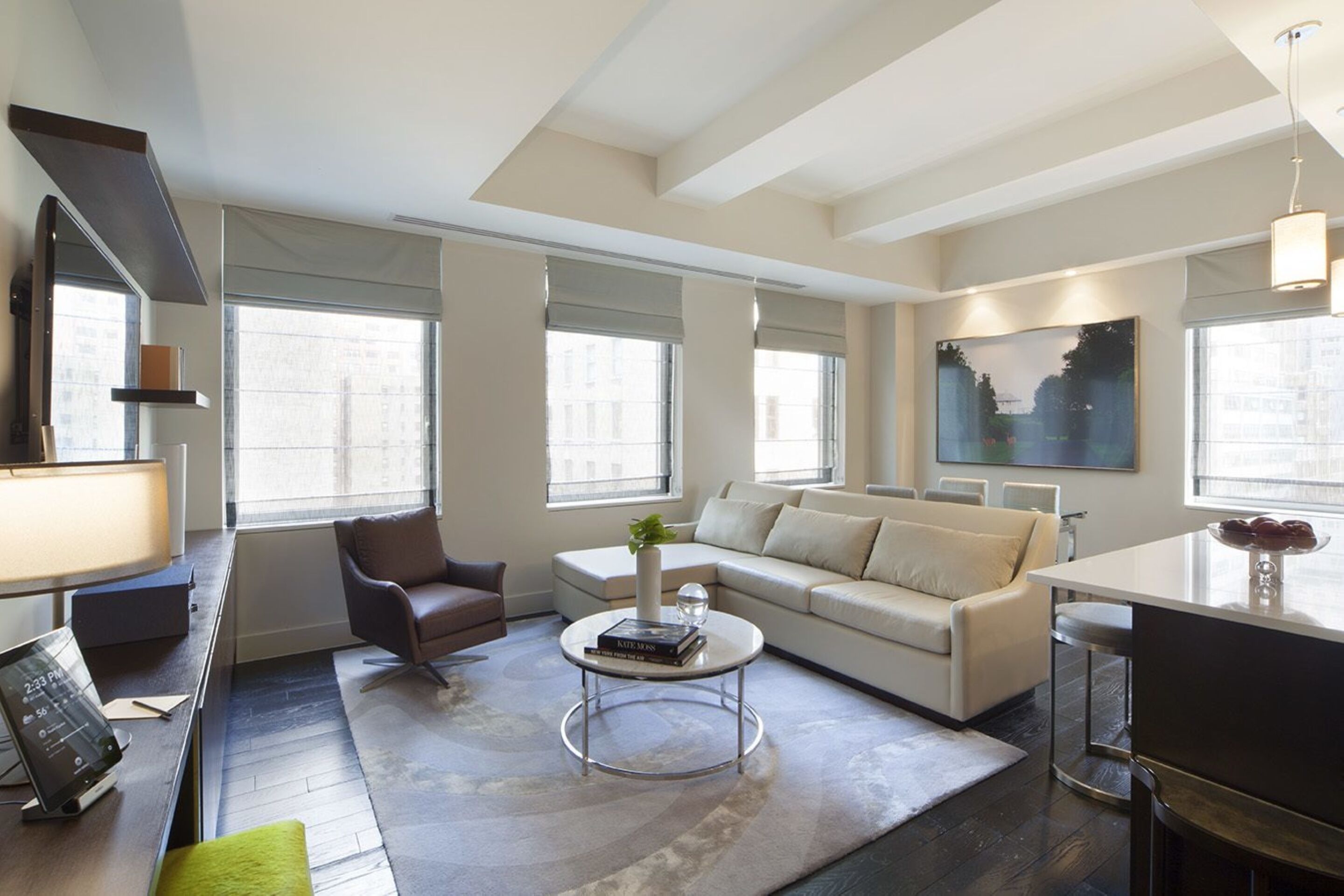 A modern living room with a sofa, armchair, coffee table, and a dining area with a table and chairs.