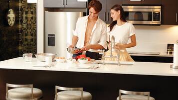 A modern kitchen with stainless steel appliances, a large island, and bar stools.
