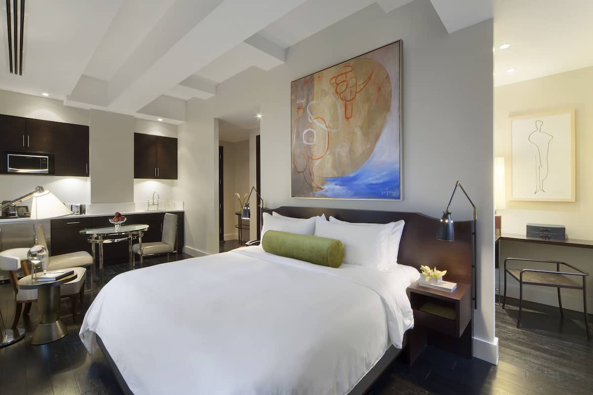 Una habitación de hotel moderna con una cama grande, un escritorio, una silla y un rincón de comedor.