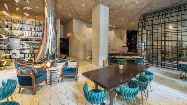 Een modern interieur met een bar, zitplaatsen en een grote tafel.