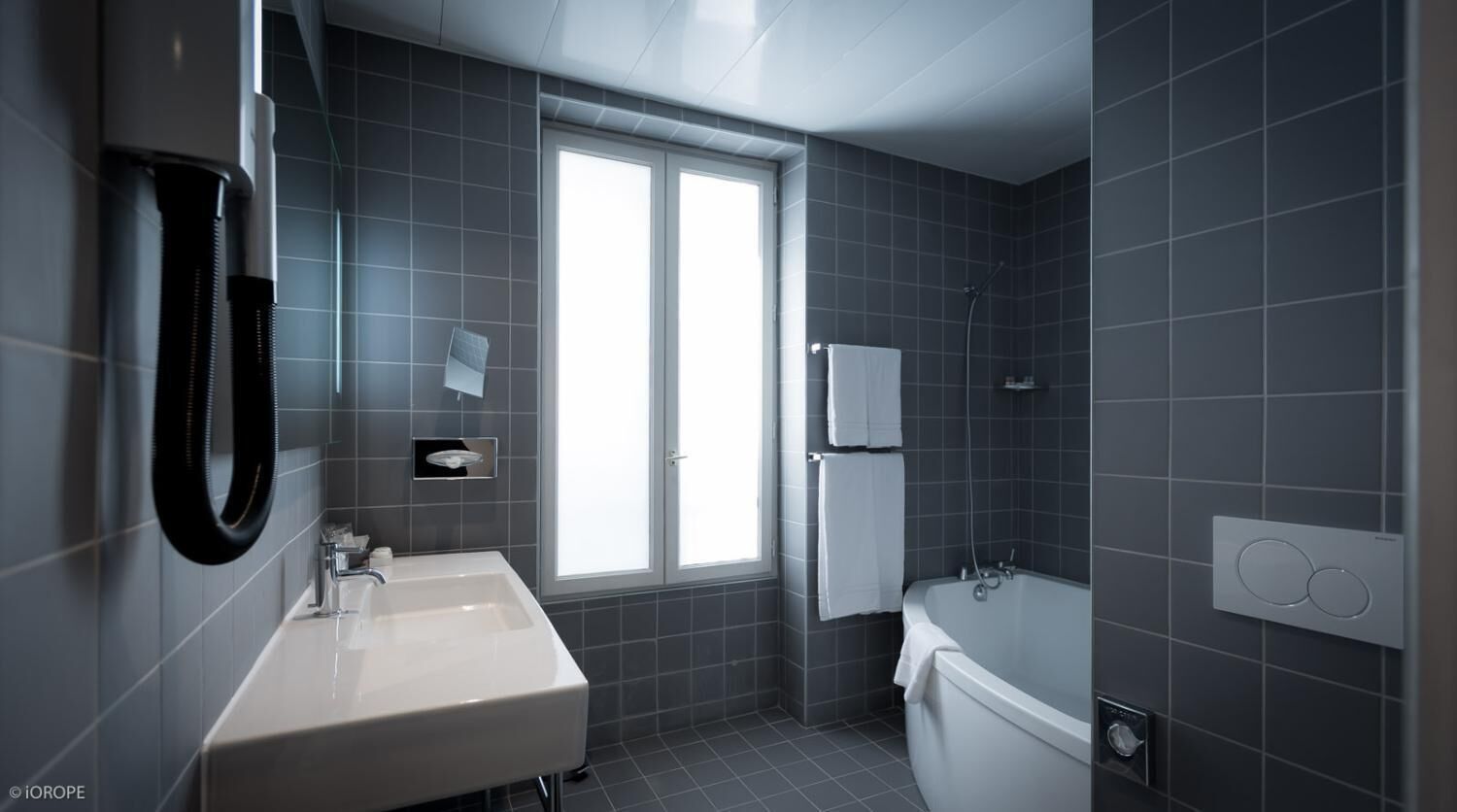 Een moderne badkamer met een wit wastafel, een bad en een raam.