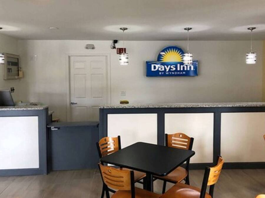 Un Days Inn by Wyndham con kitchenette, comedor con mesa y sillas, e iluminación colgante.