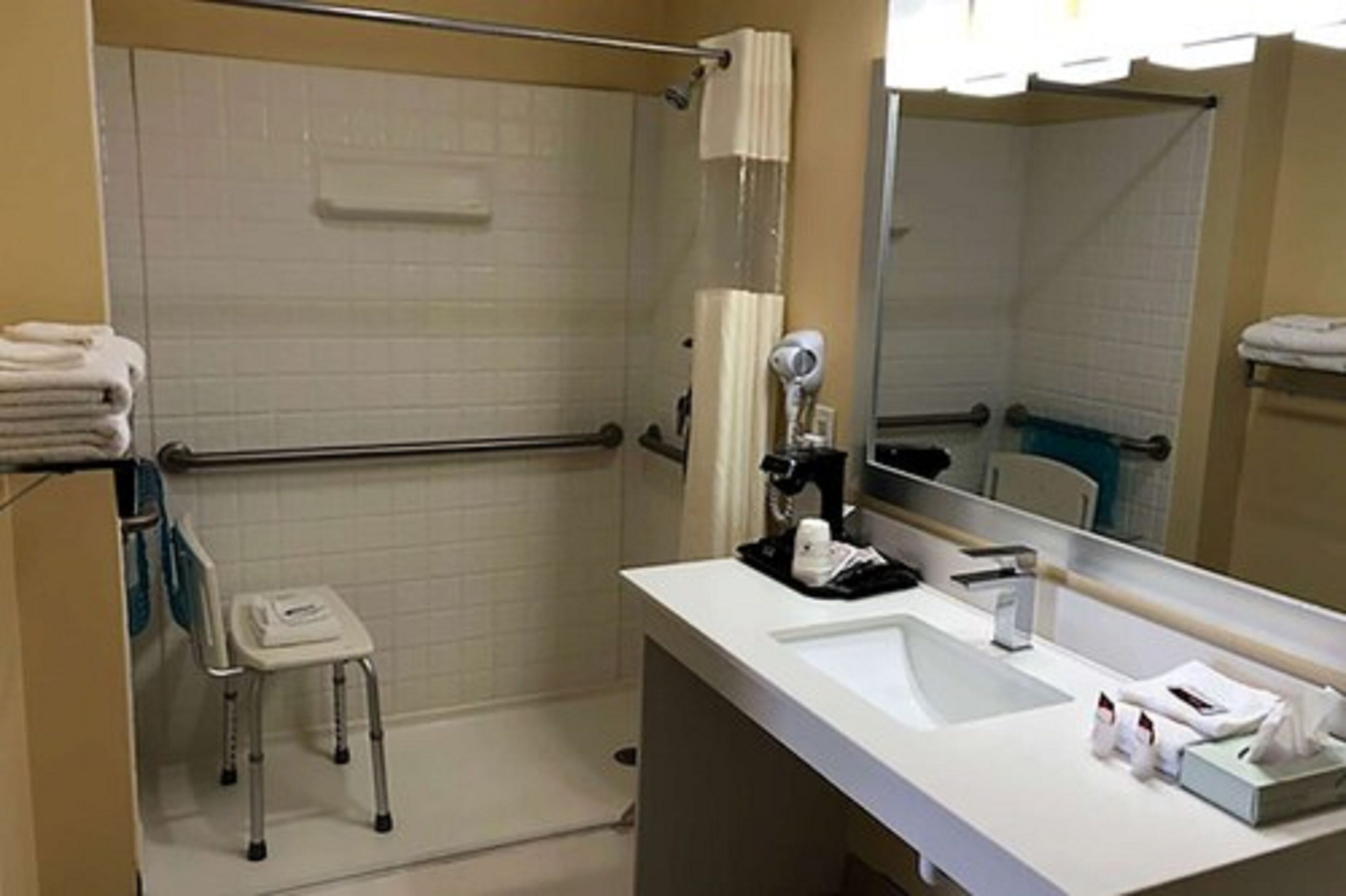 Casa de banho com lavatório branco, espelho, porta-toalhas e zona de duche.