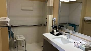 A bathroom with a white sink, a mirror, a towel rack, and a shower area.