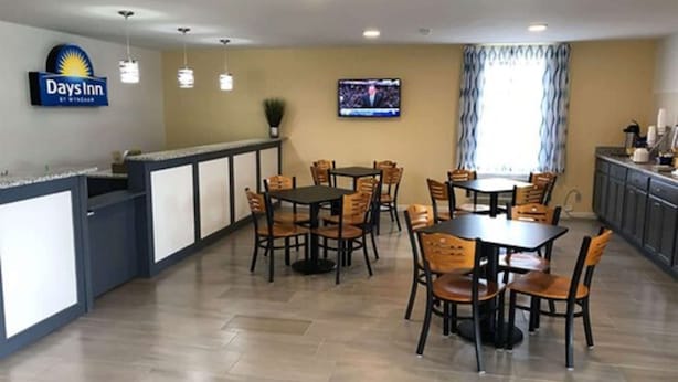 A Days Inn restaurant with a counter, multiple tables, and chairs.