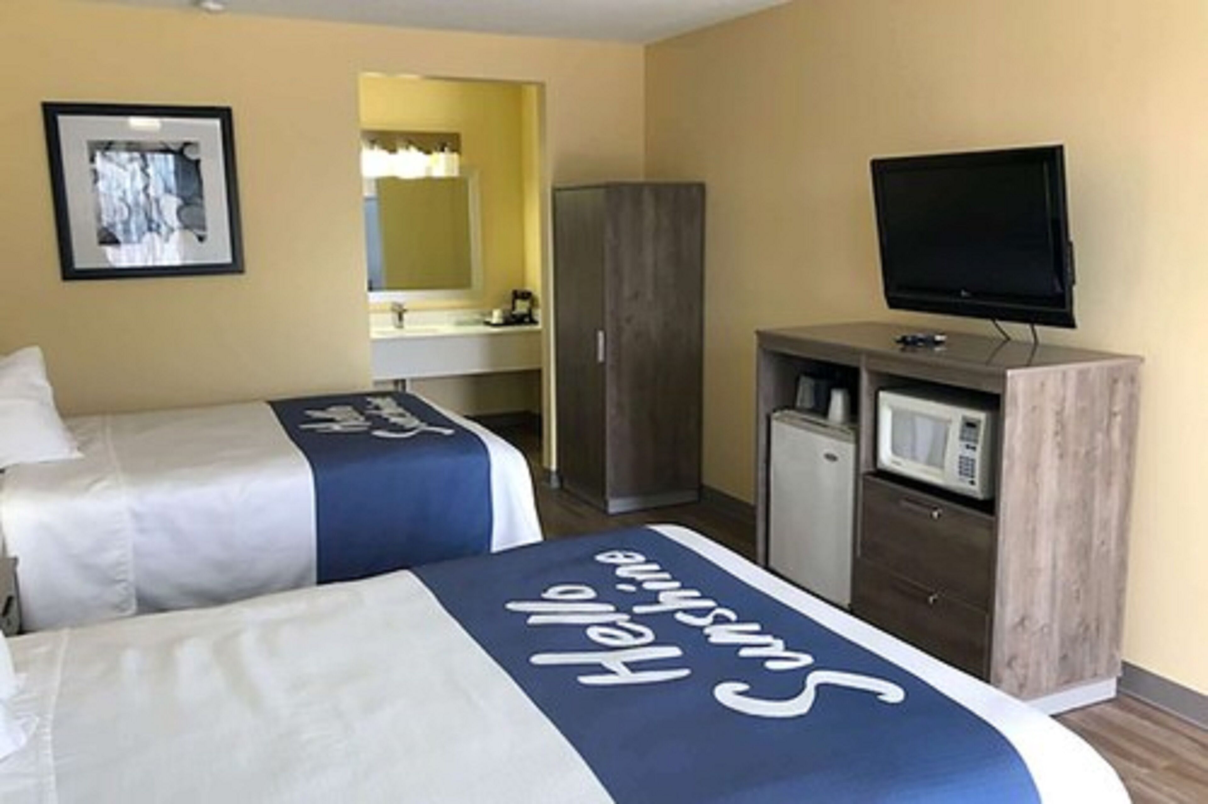 A hotel room with two beds, a television, a microwave, and a wardrobe.