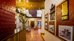A hotel lobby with a red upholstered reception desk, a chandelier, and framed photographs on the walls. - Grand Guadalupe by Inmense (San Cristóbal de las Casas)