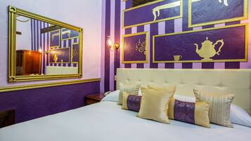 A hotel room with a large bed, a mirror, and a wall with framed pictures.