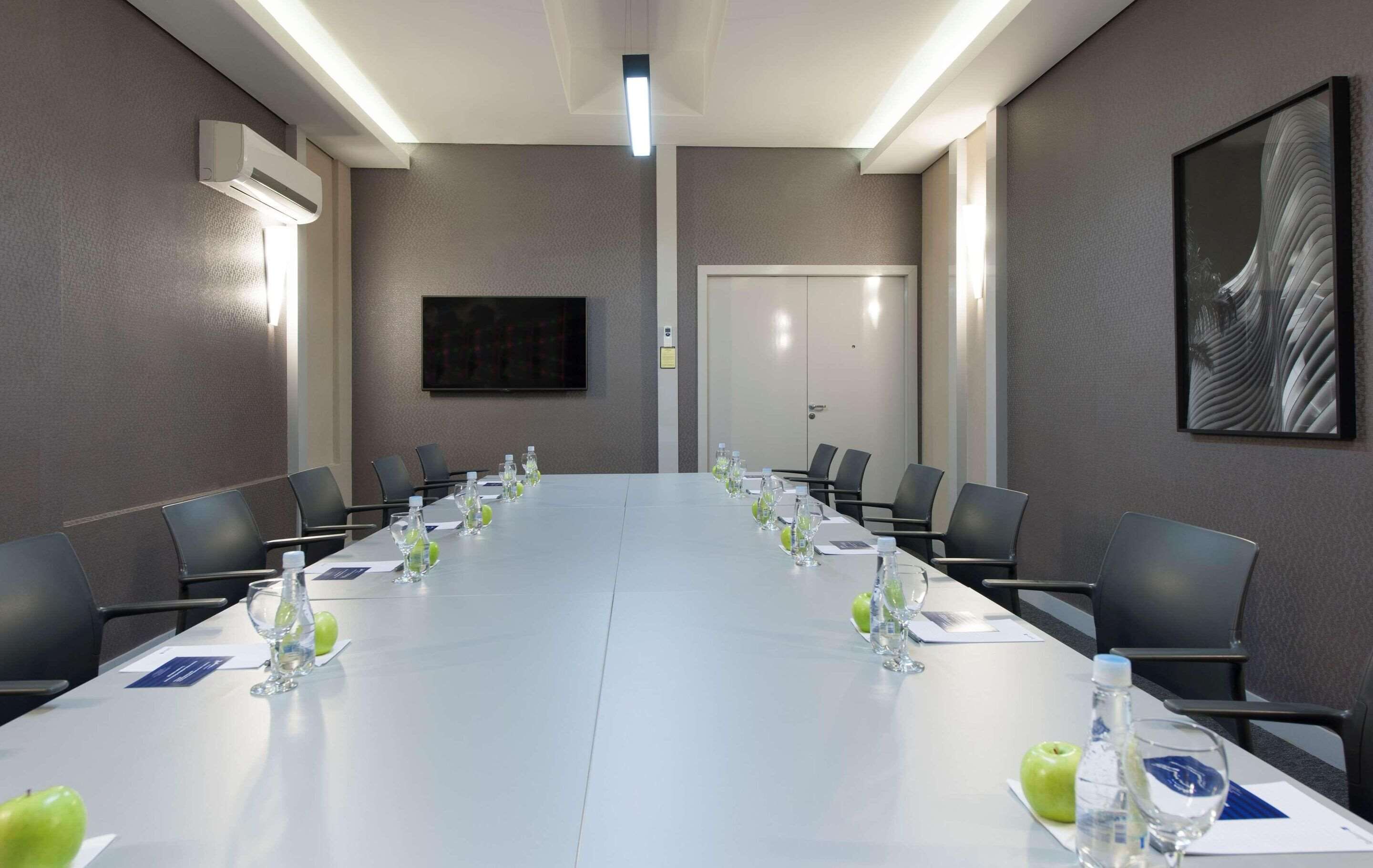 A conference room with a long table, chairs, water bottles, and name cards.