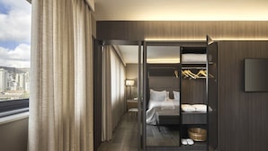 Habitación de hotel con cama, vestidor y vistas a la ciudad.