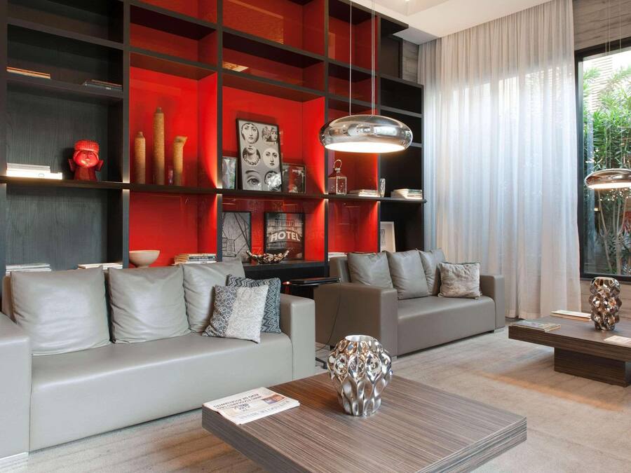 Una sala de estar moderna con sofás grises, una mesa de centro y una pared de acento roja.