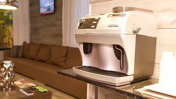 A coffee machine on a kitchen counter with a wooden wall and a brown sofa in the background.