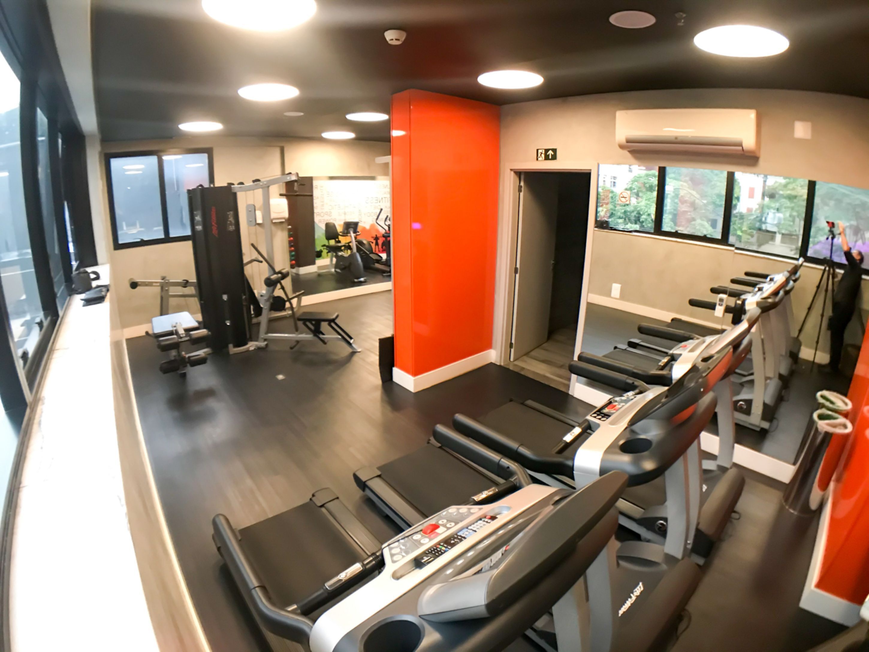 A gym with treadmills, weight machines, and a mirror wall.