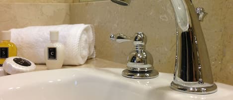 A bathroom sink with a chrome faucet, a towel, and toiletries.