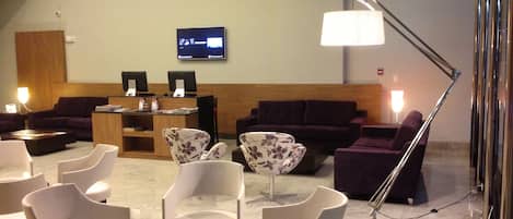 A lobby with seating areas, a reception desk, and a television screen.