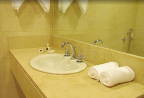 Un baño con lavamanos, espejo y toallas.