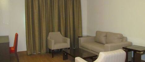 Una sala de estar con sofá, sillones, una mesa de centro y un mueble para la televisión.