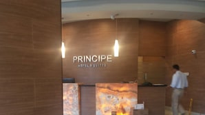 A hotel reception area with a modern design, featuring a reception desk, white chairs, and a visible fire feature. - Principe Hotel and Suites (Panama City)