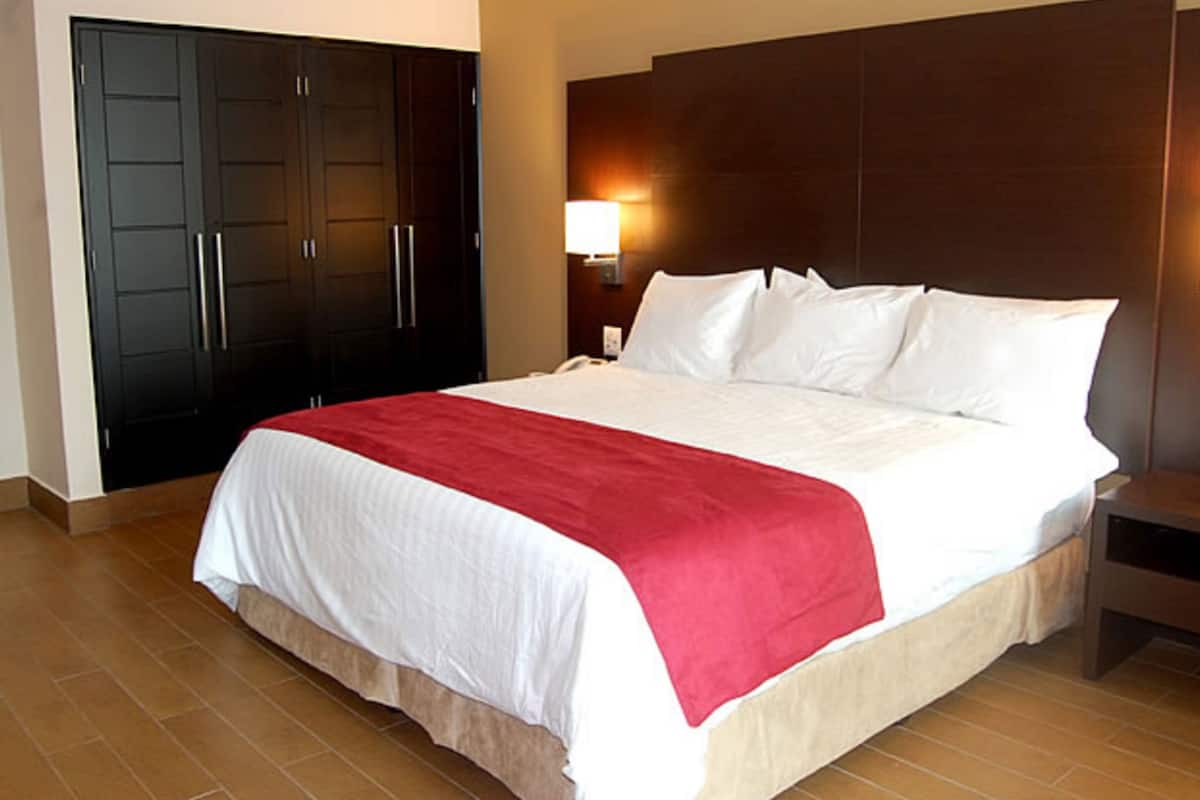 A hotel room with a large bed, a wardrobe, a bedside table, and a nightstand.