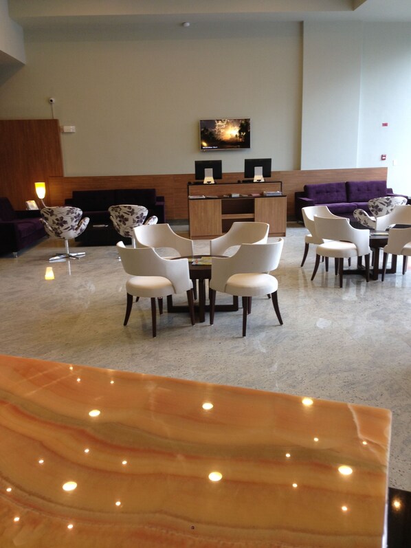 A lobby with a reception desk, purple sofas, and a seating area with white chairs. - Principe Hotel and Suites (Panama City)