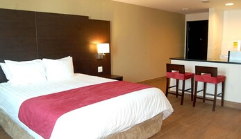 Una habitación de hotel con una cama grande, una mesita de noche, un escritorio con dos sillas y un rincón americano.