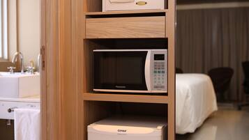 Una habitación de hotel con un mueble de madera que contiene un microondas y una caja blanca con la etiqueta 'Consul'.