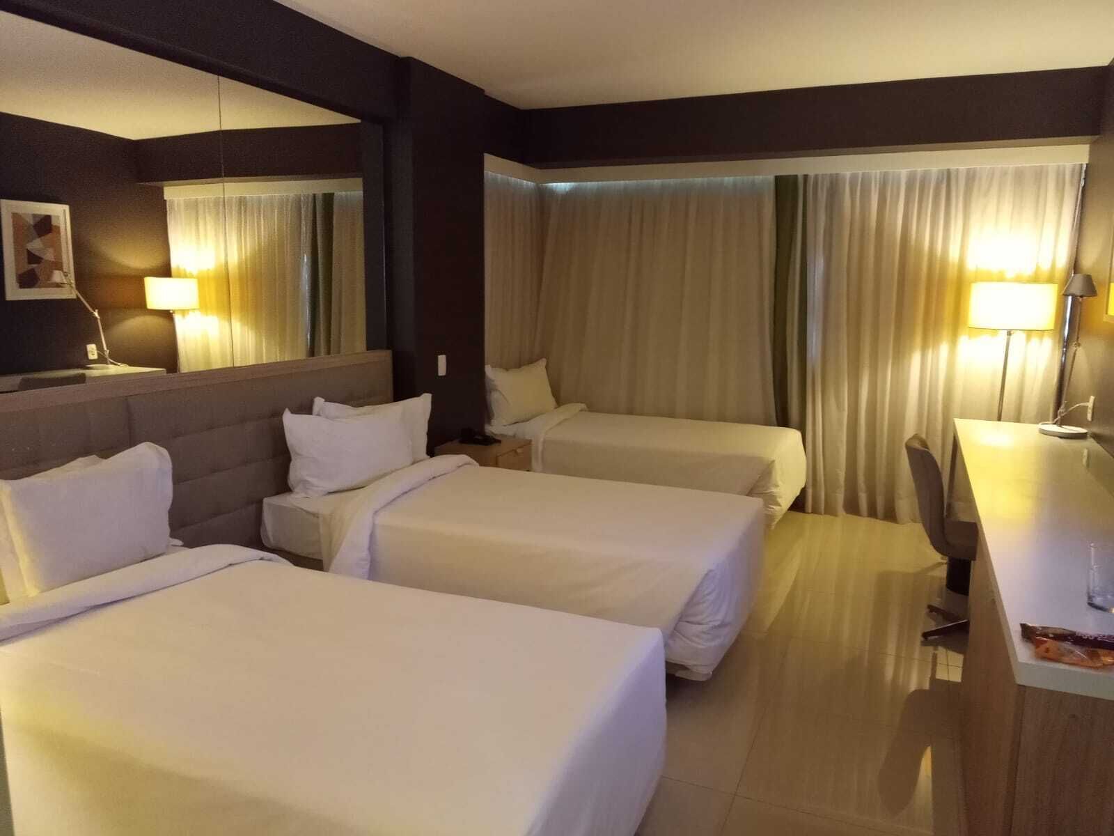 A hotel room with two beds, a desk, and a chair.