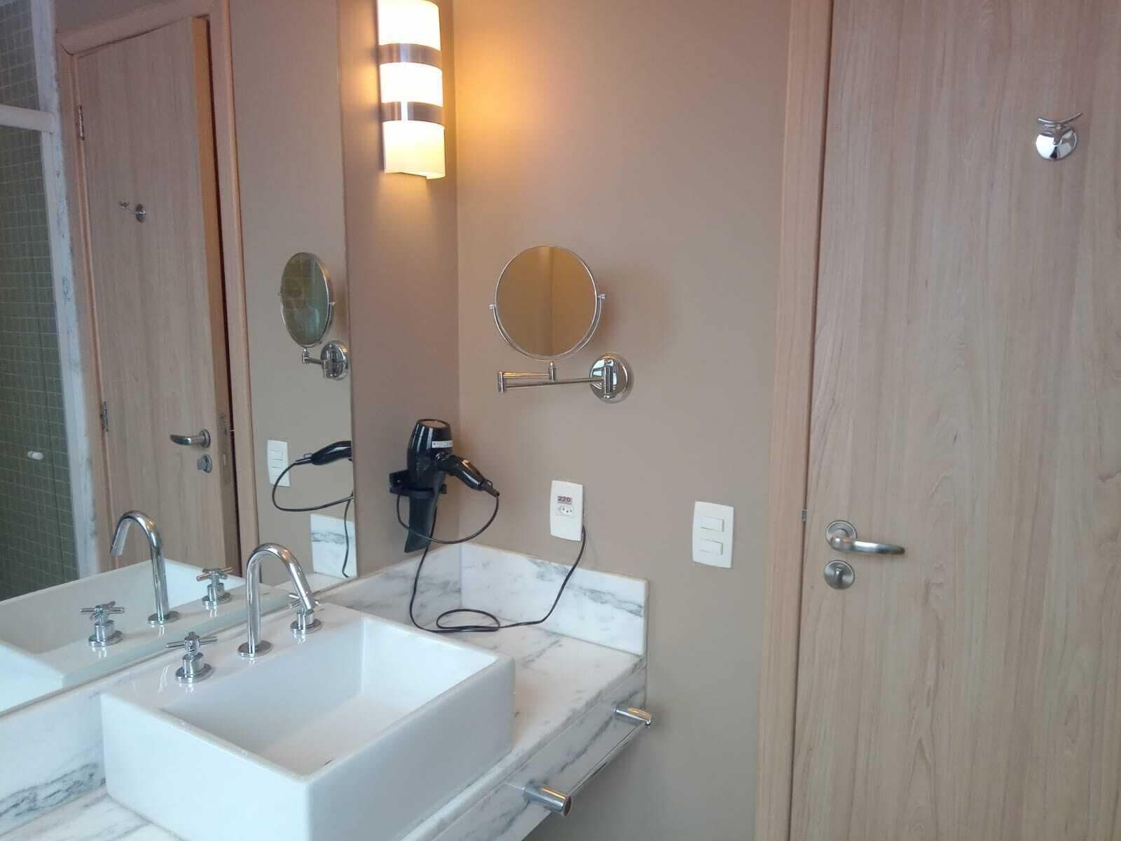 Un baño con lavamanos doble, secador de pelo y espejo.