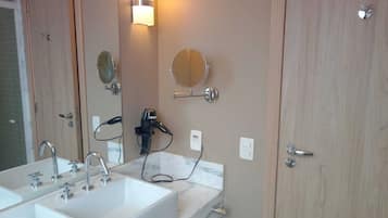 Un baño con lavamanos doble, secador de pelo y espejo.