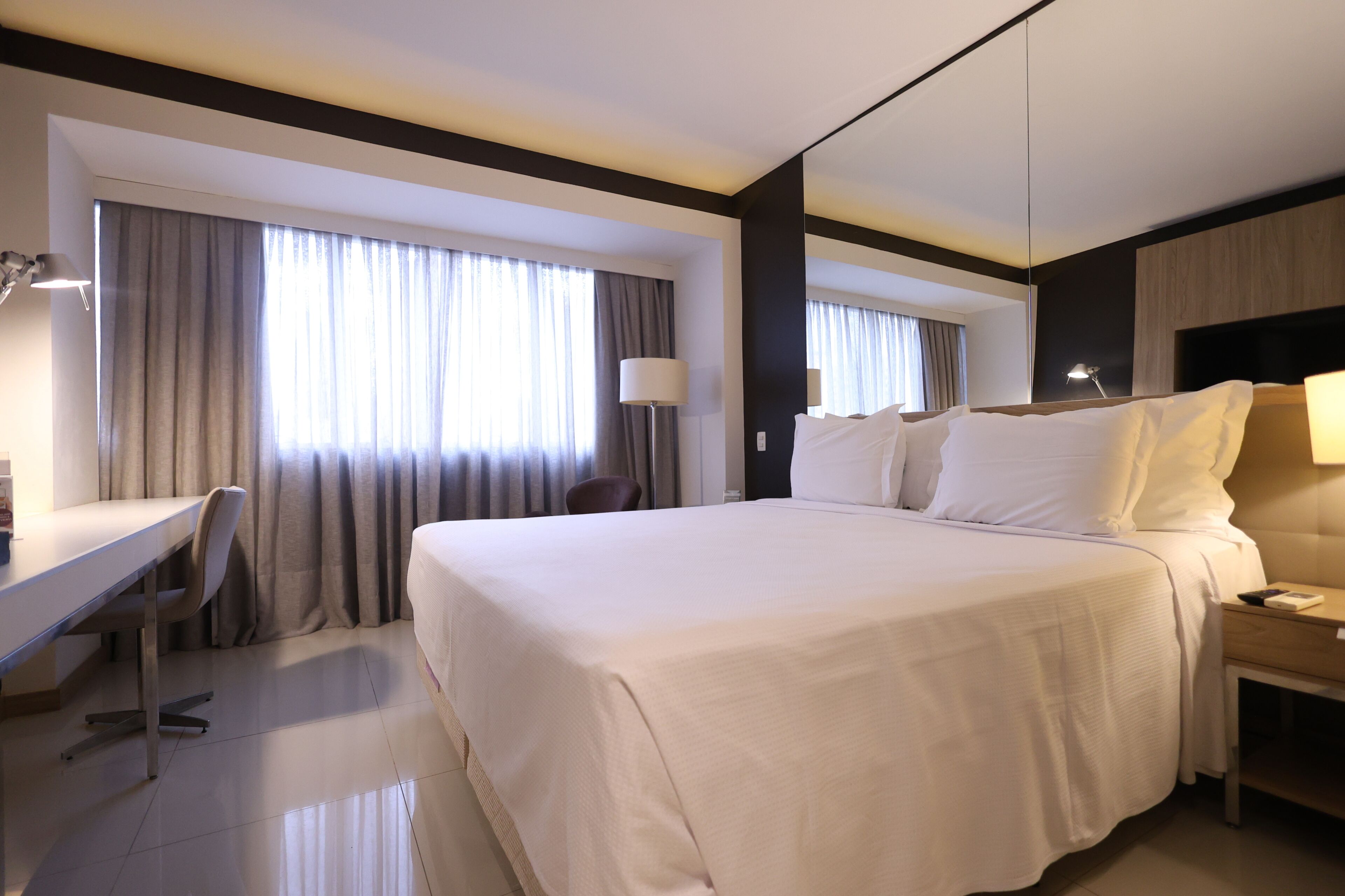 A hotel room with a large bed, a desk, and a chair.