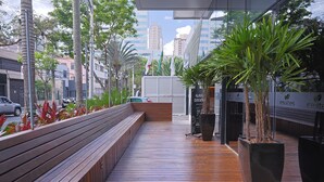 A wooden deck with benches, potted plants, and a building with signage.