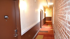 A hotel hallway with a brick wall, a carpeted floor, and a door labeled "204". - Inn on Folsom (San Francisco)