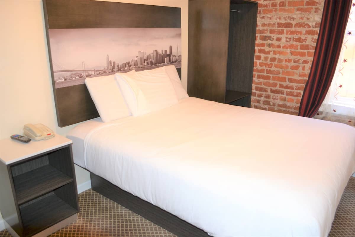 A neatly made bed with white linens in a hotel room.