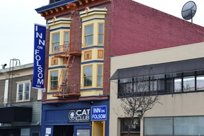 Um edifício com fachada azul e amarela, um letreiro com 'Cat Club' e um banner de 'Inn on Folsom'.