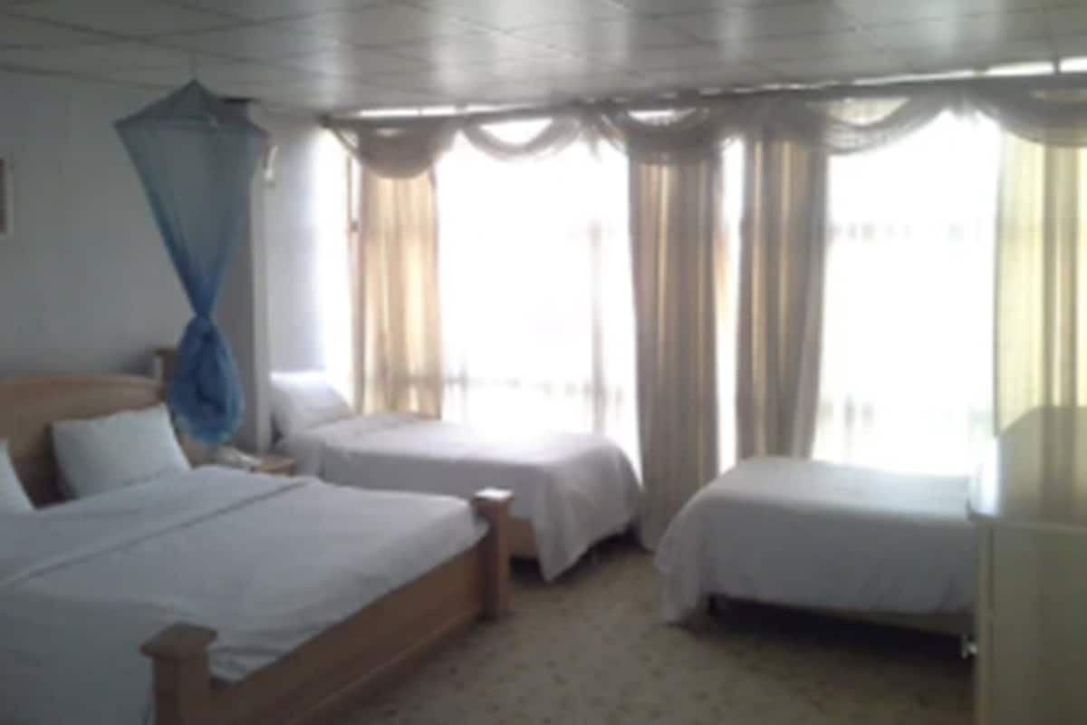 A hotel room with two single beds, a wooden headboard, and a canopy bed.