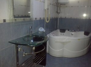 Ein Badezimmer mit einem Glaswaschbecken, einer weißen Badewanne und einem Spiegel.
