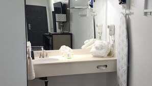 A bathroom with a sink, mirror, towel rack, and hair dryer. - Country Inn Banning (Banning)