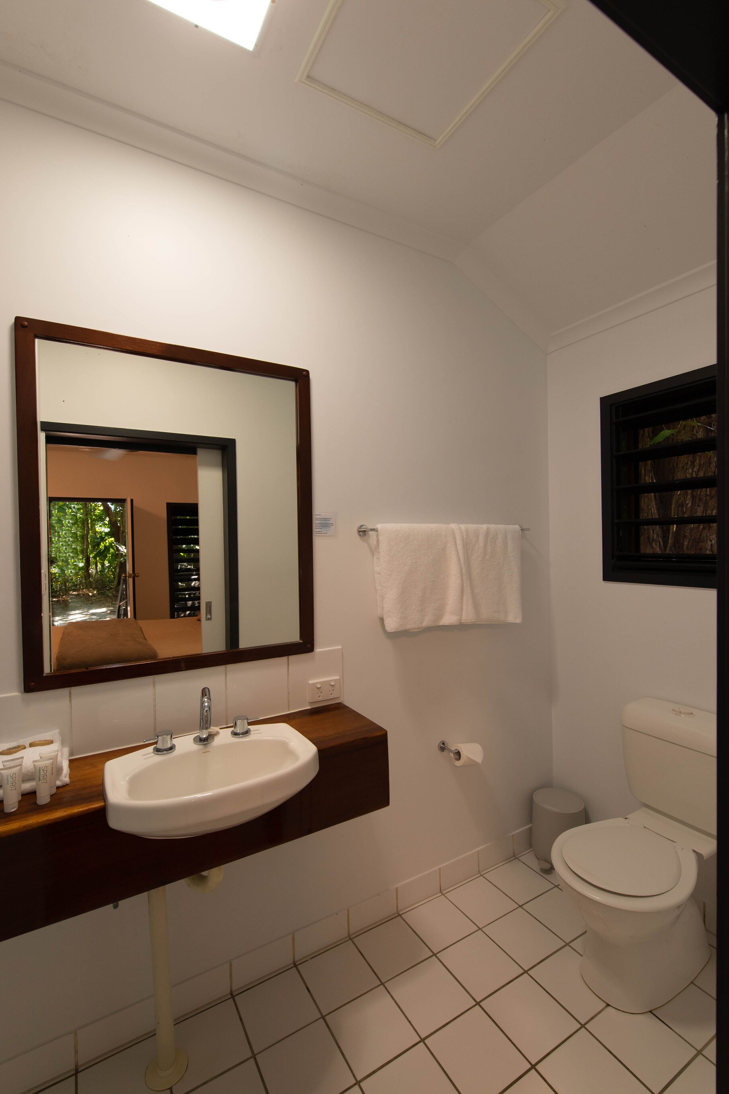 A bathroom with a white sink, mirror, and toilet.