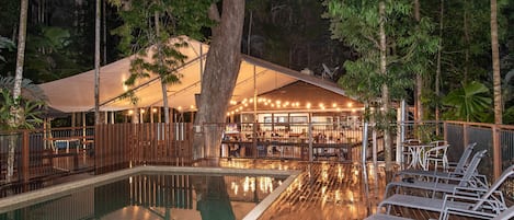 Una piscina al aire libre, sombrillas, sillones reclinables de piscina