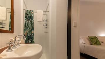 A bathroom with a sink, mirror, and shower.