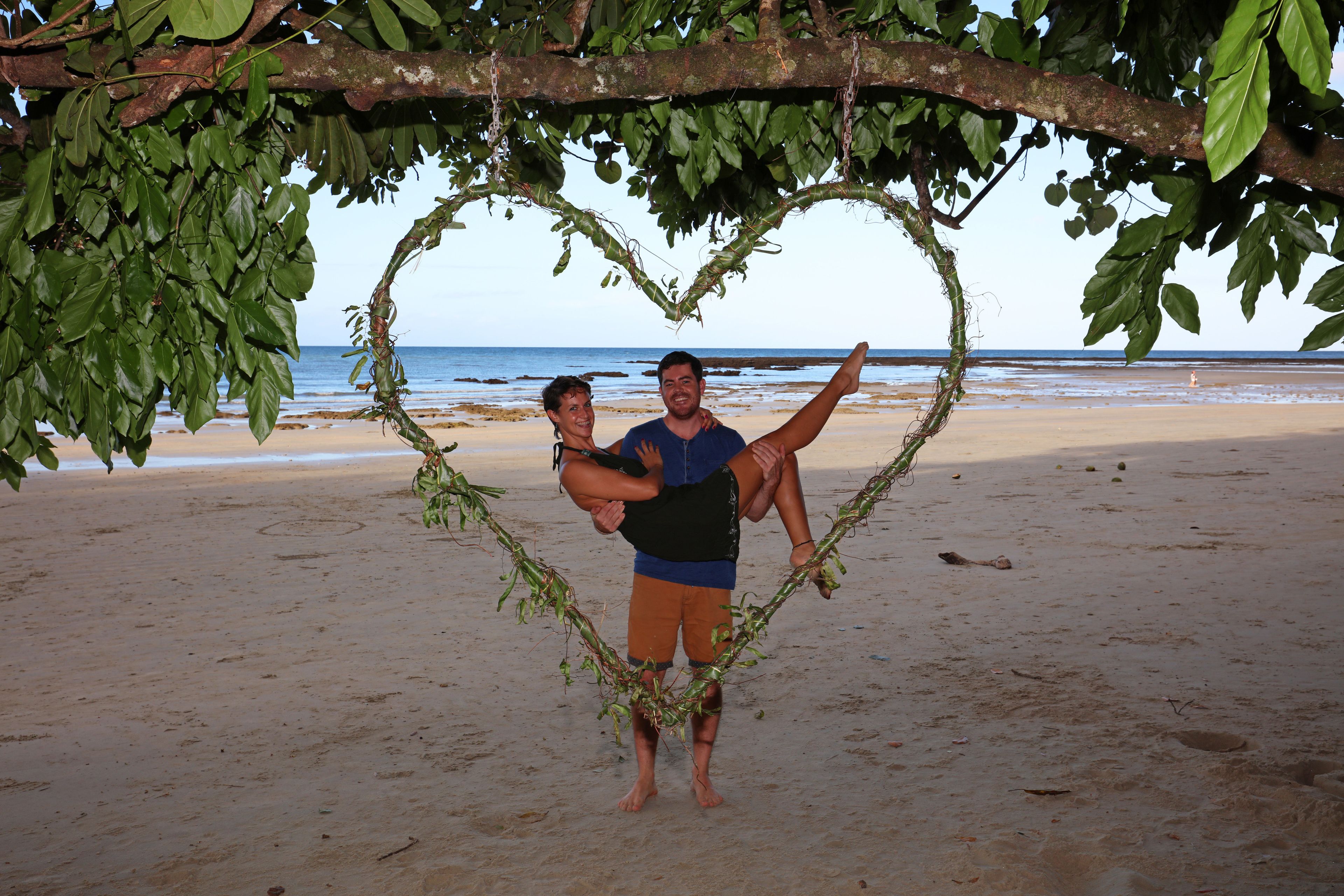 Une branche en forme de cœur sur une plage, offrant une vue dégagée sur l’océan.