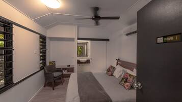 A bedroom with a bed, a chair, a nightstand, a window, and a ceiling fan.