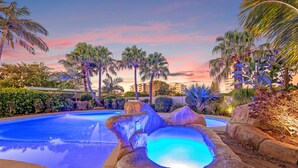 A swimming pool with a hot tub, surrounded by palm trees and a sunset sky. - The Mirage Alexandra Headland (Alexandra Headland)