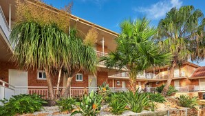 A multi-story building with balconies, surrounded by a landscaped garden with various plants and a wooden fence. - Best Western Casula Motor Inn (Casula)