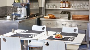 A modern hotel dining area with two tables, each with a coffee machine, a bread basket, and a plate of food. - Best Western Casula Motor Inn (Casula)