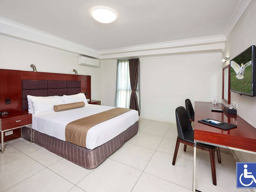 Une chambre d’hôtel comprenant un lit, une table de chevet, un bureau, une chaise et un téléviseur.