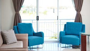 A modern living room with two blue armchairs, a beige sofa, and a patterned pillow. - Best Western Casula Motor Inn (Casula)